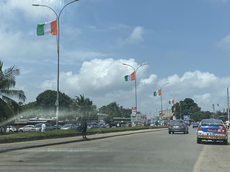Un boulevard de Yopougon sous le soleil, pavoisé aux couleurs de la Côte d’Ivoire